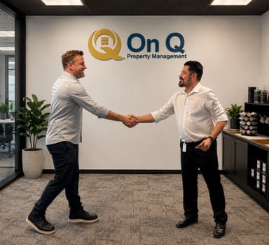 Two people shaking hands in the On Q Property Management office beneath the On Q logo